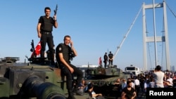 Policemen stand atop military armored vehicles after troops involved in the coup surrendered on the Bosphorus Bridge in Istanbul, Turkey, July 16, 2016.