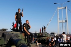 FILE - Policemen stand atop military armored vehicles after troops involved in the coup surrendered on the Bosphorus Bridge in Istanbul, July 16, 2016.