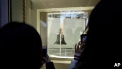 Tourists to Independence National Historical Park take photographs through a window of the closed building housing the Liberty Bell, Wednesday, Dec. 26, 2018, in Philadelphia. The building is closed due to the partial government shutdown.