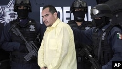 Federal police officers escort suspect Marco Antonio Guzman, aka 'El Brad Pitt,' an alleged member of the Mexican Juarez drug cartel, during a presentation to the press in Mexico City, Thursday, June 16, 2011