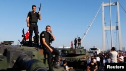 FILE - Policemen stand atop military armored vehicles after troops involved in the coup surrendered on the Bosphorus Bridge in Istanbul, Turkey, July 16, 2016.