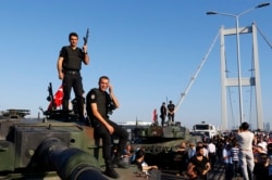 FILE - Policemen stand atop military armored vehicles after troops involved in the coup surrendered on the Bosphorus Bridge in Istanbul, Turkey, July 16, 2016.