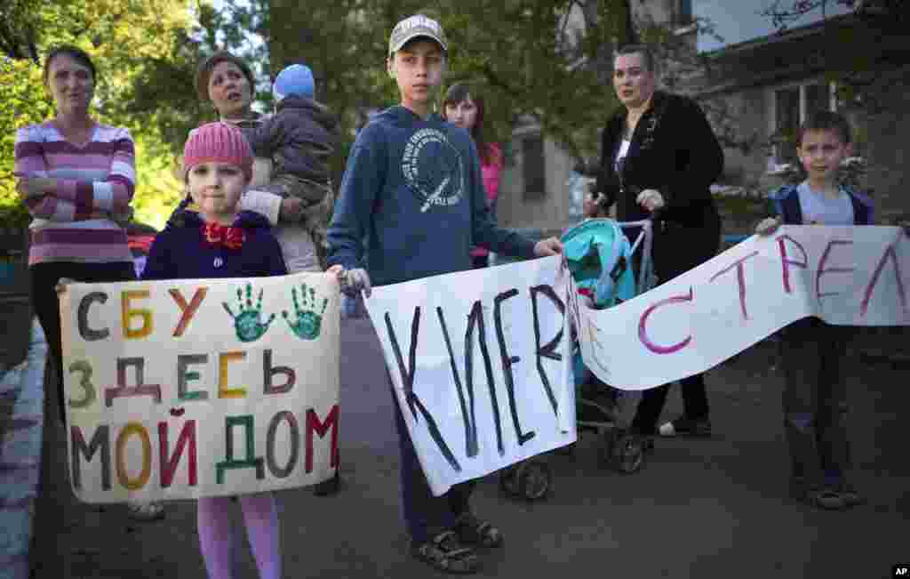 Local citizens and their children hold posters that read: "Ukrainian Regional Security Service, Here is my Home" and "Kiev, Do Not Shoot", during anti-war action in Slovyansk, Ukraine, Wednesday, May 7, 2014. Ukrainian military operations that began Monday to expunge pro-Russia forces from the city of Slovyansk were the interim government's most ambitious effort so far to quell weeks of unrest in Ukraine's mainly Russian-speaking east. (AP Photo/Alexander Zemlianichenko)