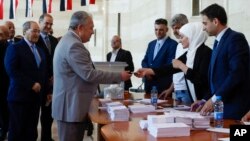 (FILE) Syrian Prime Minister Hussein Arnous and Syrian Foreign Minister Faisal Mekdad arrive to a polling station to cast their votes during the Syrian parliamentary election in Damascus, Syria, Monday, July 15, 2024.