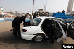 FILE - Police officers search a vehicle at a checkpoint, as security increases after a bomb attack, at Abu Ghraib district, west of Baghdad, Iraq, Jan. 9, 2014.