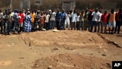Local residents look on as republican forces soldiers visit the site of an alleged mass grave in a recently pacified area of the Yopougon district, in Abidjan, Ivory Coast, May 5, 2011