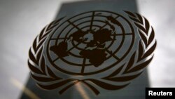 FILE - The United Nations headquarters building is pictured though a window with the U.N. logo in the foreground.