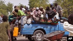 Mutanen kauye a zaune a bayan wata mota a lokacin da suke tserewa rigingimu a kusa da birnin Maiguduri. 