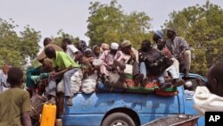 Mutanen kauye a zaune a bayan wata mota a lokacin da suke tserewa rigingimu a kusa da birnin Maiguduri. 