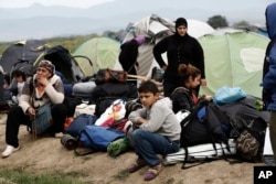 Refugees and migrants wait to embark into the buses during a police operation at a makeshift refugee camp at the Greek-Macedonian border near the northern Greek village of Idomeni, May 24, 2016.