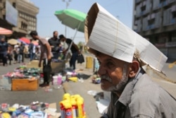 An Iraqi street vendor protects his head from the sun by using a piece of cardboard as a hat during a heat wave in the capital Baghdad, June 14, 2019.