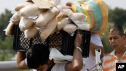 A Venezuelan man carries a crate filled with bread back to his country, in La Parada, on the outskirts of Cucuta, Colombia, on the border with Venezuela, Feb. 4, 2019.