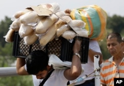 A Venezuelan man carries a crate filled with bread back to his country, in La Parada, on the outskirts of Cucuta, Colombia, on the border with Venezuela, Feb. 4, 2019.