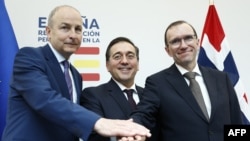 Spanish Minister for Foreign Affairs, European Union and Cooperation, Jose Manuel Albares (C), Norwegian Foreign Minister Espen Barth Eide (R) and Irish Foreign minister Micheal Martin join hands after holding a joint press conference at the the Permanent