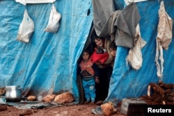 FILE - Displaced Syrian children look out from their tents at Kelbit refugee camp, near the Syrian-Turkish border, in Idlib province, Syria, Jan. 17, 2018.