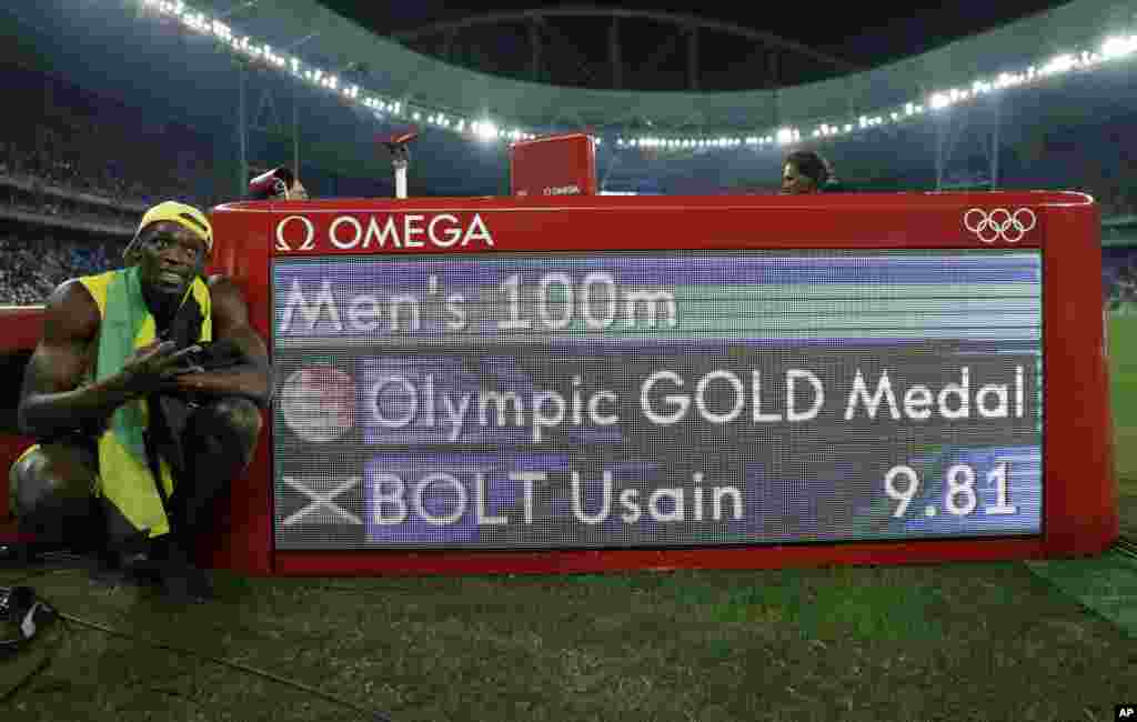 Usain Bolt de la Jamaïque pose à côté du panneau de chronométrage après avoir remporté la médaille d&#39;or en finale de 100 mètres hommes à Rio de Janeiro, Brésil, 14 août 2016. 
