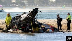 Emergency workers inspect a helicopter at a scene collision near Seaworld, on the Gold Coast, Australia, Jan. 2, 2023. 