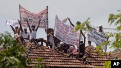 Para terpidana mati melakukan aksi protes di penjara Welikada di Kolombo, Sri Lanka, dengan memegang spanduk dari atap penjara, Jumat, 25 Juni 2021. (AP Photo/Eranga Jayawardena)