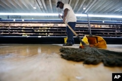 Randy Davis, manager at the Circle Food Store, mops the floor after the store flooded from the past weekend's torrential rains, in New Orleans, Aug. 7, 2017.