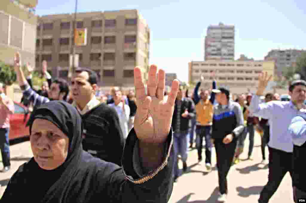 Protesters march through Cairo holding up four-fingers, a hand sign in memory of last year's deadly crackdown on supporters of ousted President Mohamed Morsi, March 28, 2014. (Hamada Elrassam/VOA)