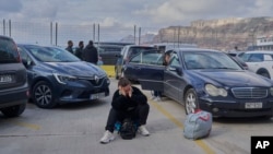 A passenger sits on the dock while waiting for a ferry bound for the Greek mainland, in the earthquake-struck island of Santorini, Greece, Feb. 4, 2025.