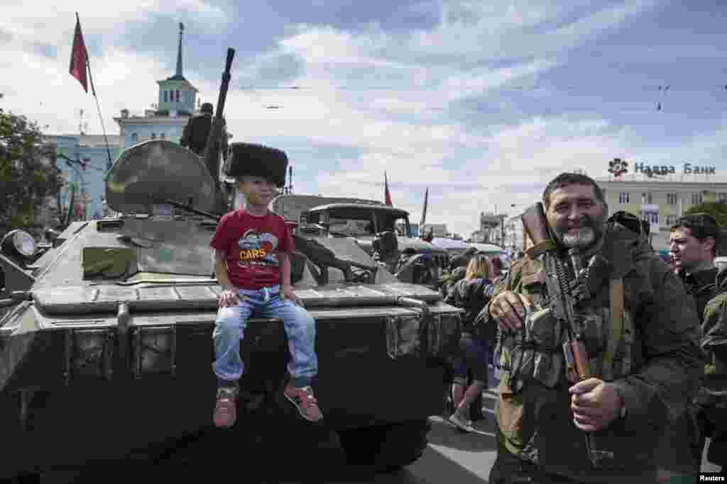 A boy sits on an armored personnel carrier posing for a picture during a parade in Luhansk, eastern Ukraine, Sept. 14, 2014.