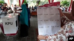 A woman shows a mock national legislature ballot during a polling simulation exercise held by the election commission in Jakarta, Indonesia, Apr. 10, 2019.