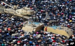 FILE - In this Feb. 11, 2011, photo, anti-government protesters, and Egyptian soldiers on top of their vehicles, make traditional Muslim Friday prayers at the continuing demonstration in Tahrir Square in downtown Cairo, Egypt.