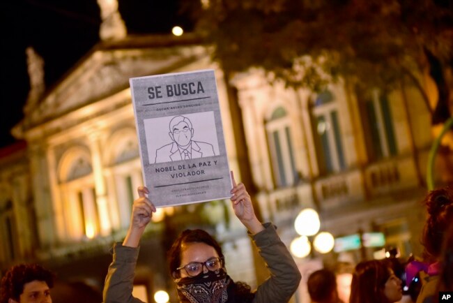 FILE - A woman holds up a sign with a line drawing depicting Costa Rica’s ex-President Oscar Arias and a message that reads in Spanish: “WANTED: Oscar Arias Nobel Peace Prize laureate and Violator,” during a protest by women activists under the slogan "Yo te creo," or "I believe you,” in San Jose, Costa Rica, Feb. 8, 2019.