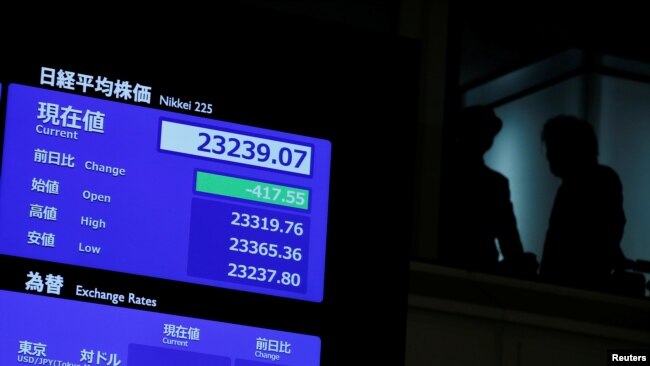Los asistentes se ven junto a una pantalla que muestra el índice de precios de las acciones después de la ceremonia de apertura de Año Nuevo en la Bolsa de Valores de Tokio (TSE), celebrada para desear el éxito del mercado de valores de Japón en Tokio, Japón, el 6 de enero de 2020. REUTERS / Kim Kyung -Hoon