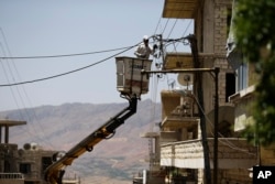A Syrian electricity worker fixes power cables, at the town of Madaya in the Damascus countryside, Syria, May 18, 2017.