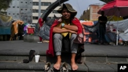 El inmigrante venezolano Cristo Pérez, de 33 años, sentado al sol en un campamento de migrantes frente a la Iglesia de La Soledad en la Ciudad de México, el 31 de julio de 2024. 