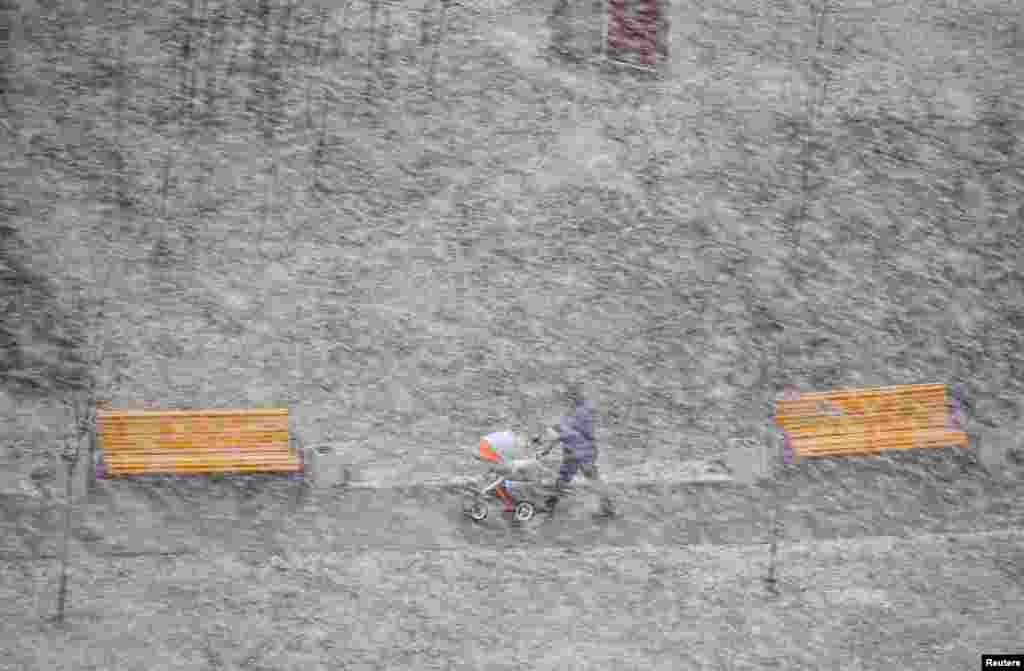 A man with a pram walks during heavy snowfall in Minsk, Belarus.