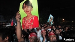 Supporters celebrate holding posters of Aung San Suu Kyi as election results are displayed on a screen in front of Burma's National League for Democracy head office in Yangon April 1, 2012.