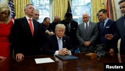 Faith leaders place their hands on the shoulders of U.S. President Donald Trump as he takes part in a prayer for those affected by Hurricane Harvey in the Oval Office of the White House in Washington, Sept. 1, 2017.