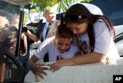 FILE - Adriana Maria dos Santos, mother of the late Vanessa do Santos, and a friend, Laisa, cry over Vanessa's casket during her burial in Rio de Janeiro, Brazil, July 6, 2017. The 10-year-old child was killed two days earlier after being hit in the head