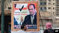 People walk past a banner supporting proposed amendments to the Egyptian constitution with a poster of Egyptian President Abdel-Fattah el-Sissi in Cairo, Egypt, April 16, 2019. 