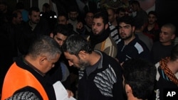 An Arab league observer, left, with orange vest, writes the names of freed Syrian prisoners as they are released from Adra Prison on the north-east outskirts of Damascus, Syria, January 15, 2012.