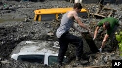 Residents try to excavate a car trapped in the mud caused by a landslide at the village of Topcic Polje, near Zenica, Bosnia-Herzegovina, May 20, 2014.