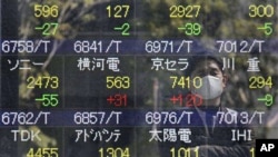 A reflection of a man who looks at the stock price board is seen in Tokyo, March 17, 2011