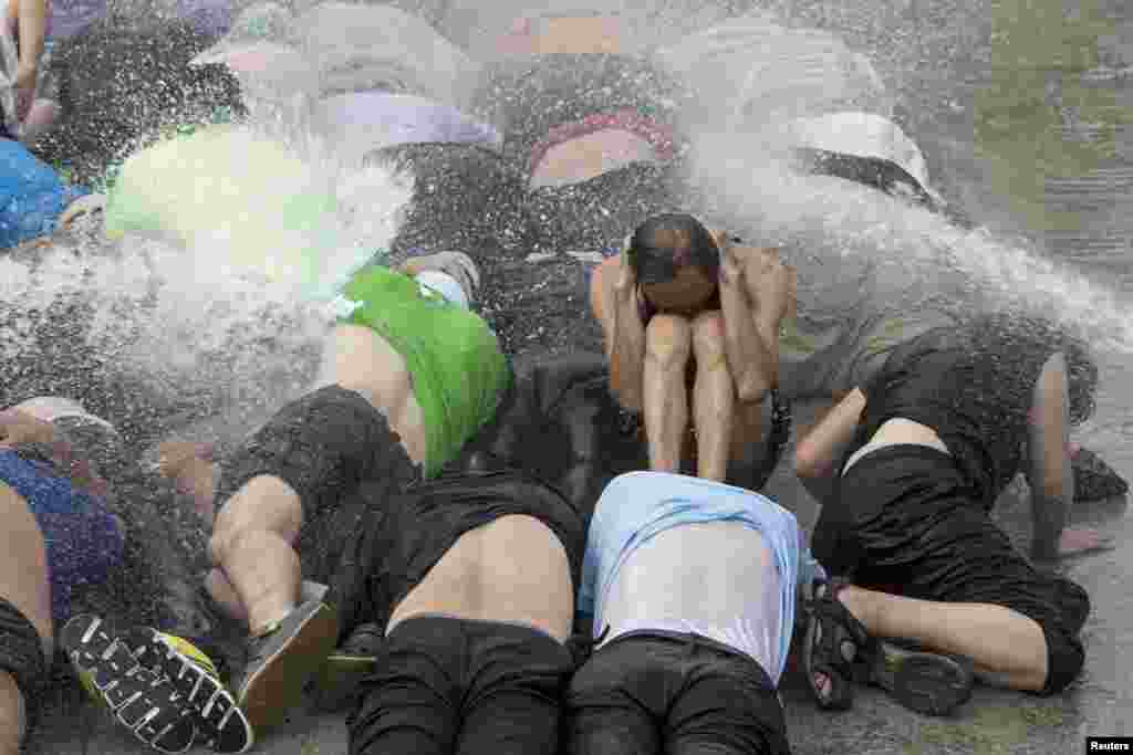 Pro-democracy activists brace themselves during a drill to simulate the scenario of being sprayed with a water cannon at the upcoming &quot;Occupy Central&quot; movement rally in Hong Kong.