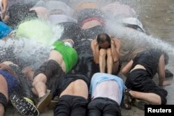 香港民主派活动人士为“占中”运动演练经受高压水龙头攻击。（2014年9月7日）