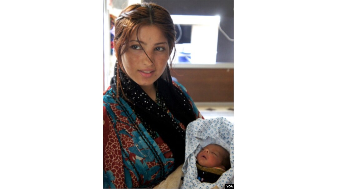 A young mother, displaced from Aleppo, cares for her newborn at a government center in Dummar, Syria. (E. Arrott/VOA)