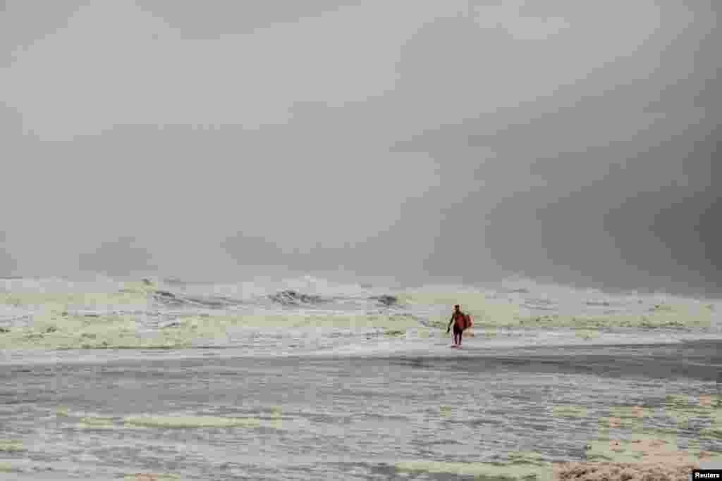 Tyler Wickline walks toward his friend after an unsuccessful surf due to extremely high tides and winds caused by Hurricane Dorian in Jacksonville, Florida.