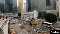 A worker loads debris onto a truck at an area, previously blocked by pro-democracy protesters, near the government headquarters building at the financial Central district in Hong Kong, December 11, 2014.