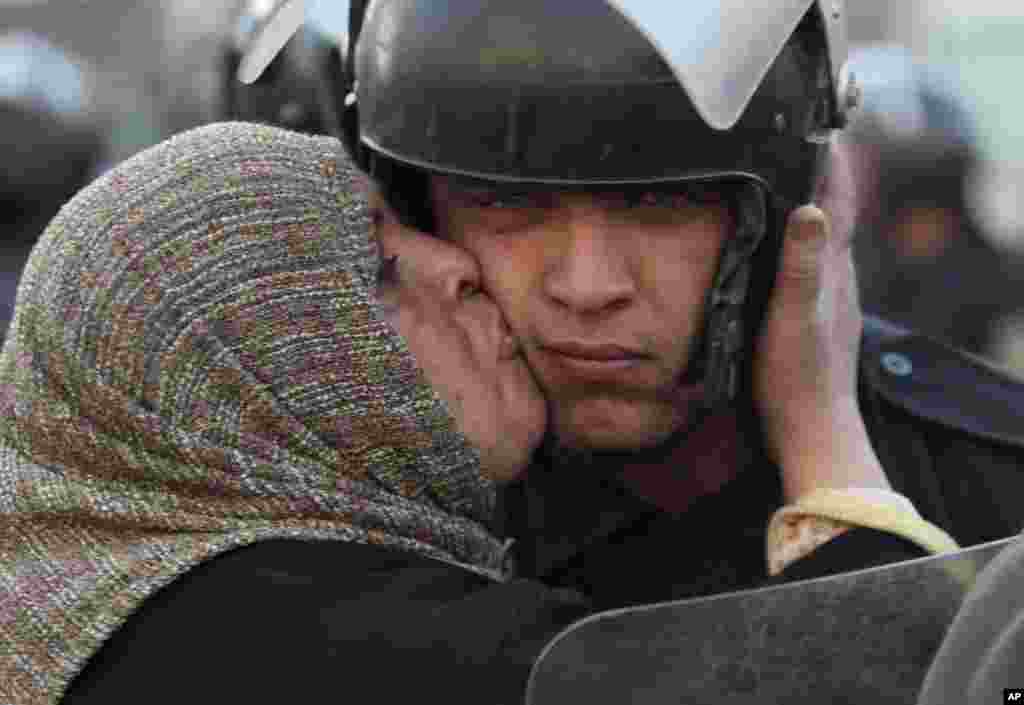 An Egyptian anti-government activist kisses a riot police officer following clashes in Cairo, Egypt, Friday, Jan. 28, 2011