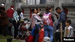 FILE - Venezuelan migrants wait on the grounds of their country's embassy for a bus that will transport them to the airport, in Lima, Peru, Sept. 8, 2018. 