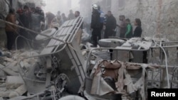 Men inspect a site hit by what activists said was a barrel bomb dropped by forces loyal to Syria's President Bashar al-Assad on al-Marjeh neighborhood of Aleppo, Nov. 12, 2014. 