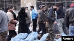 Free Syrian Army fighters and residents attempt to identify bodies found along a river, at a school used as a field hospital in Aleppo, Syria, January 29, 2013