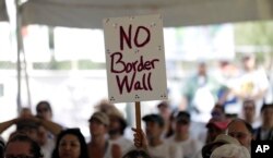 FILE - A "No border wall" sign is held up during a rally to oppose the wall the U.S. government wants to build on the river separating Texas and Mexico, Aug. 12, 2017, in Mission, Texas.